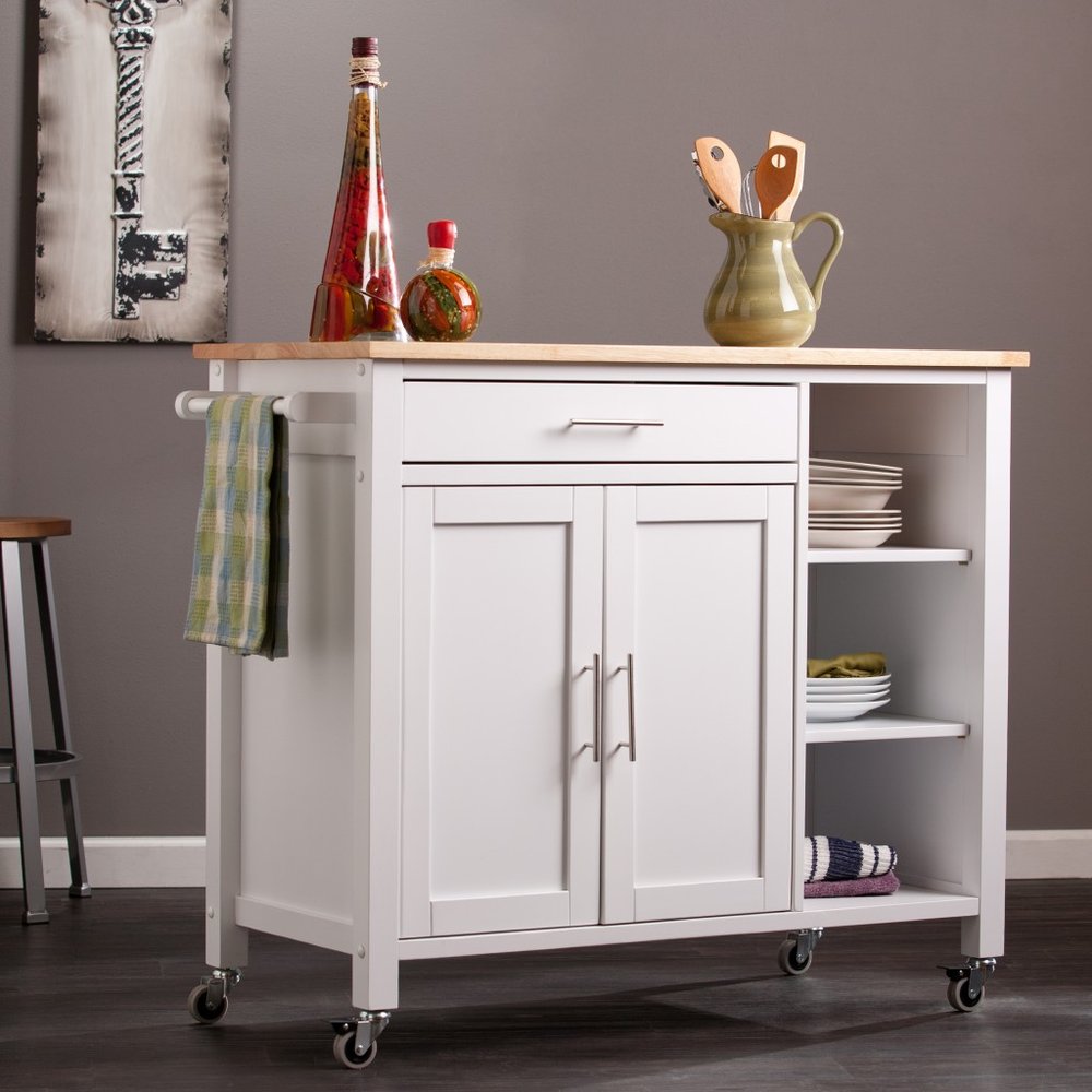 42" Natural and White Butcher Block and Iron Rolling Kitchen Cart With Storage styled in a furnished interior with a brown wall on a charcoal floor in tan metal.
