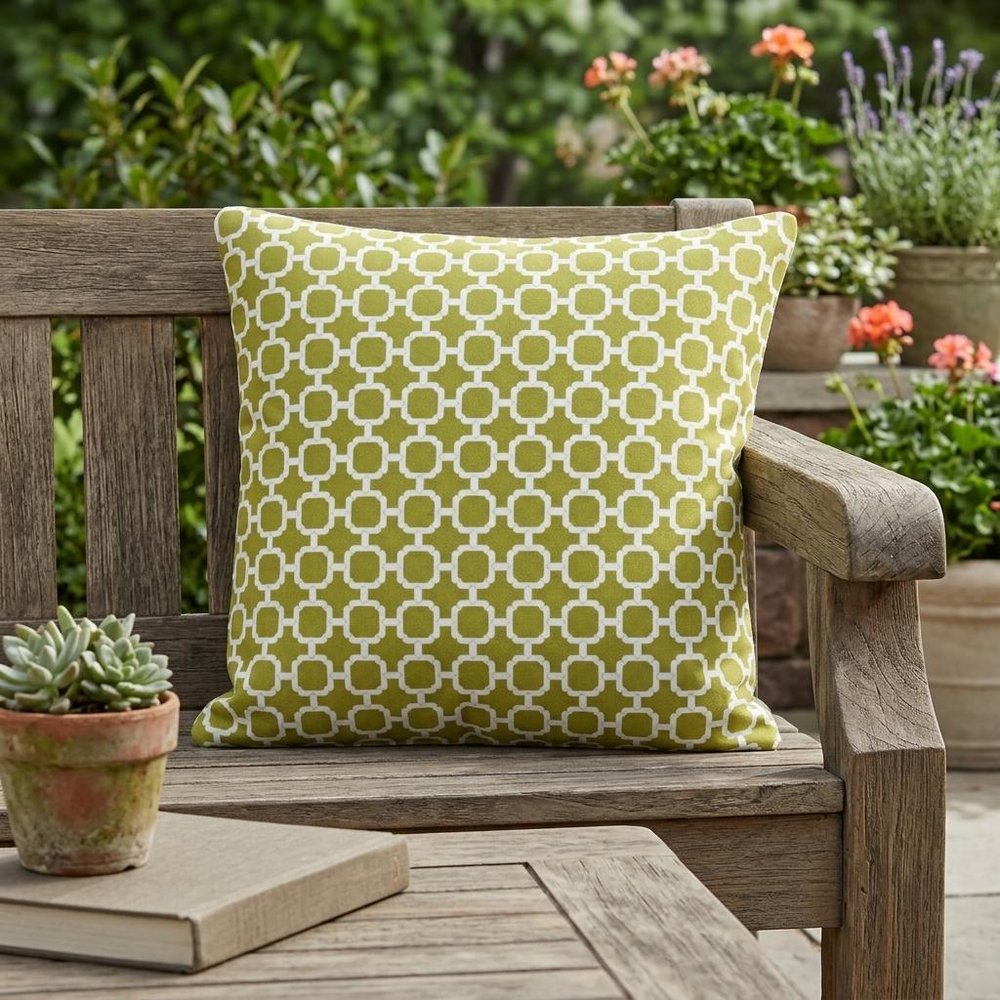 22" Green and White Quatrefoil Indoor Outdoor Throw Pillow shown outdoors on a patio with greenery.