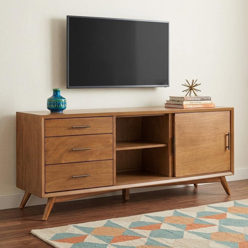 64" Brown TV Stand with Drawers and Sliding Door styled in a furnished interior with an off-white wall on a dark wood floor.