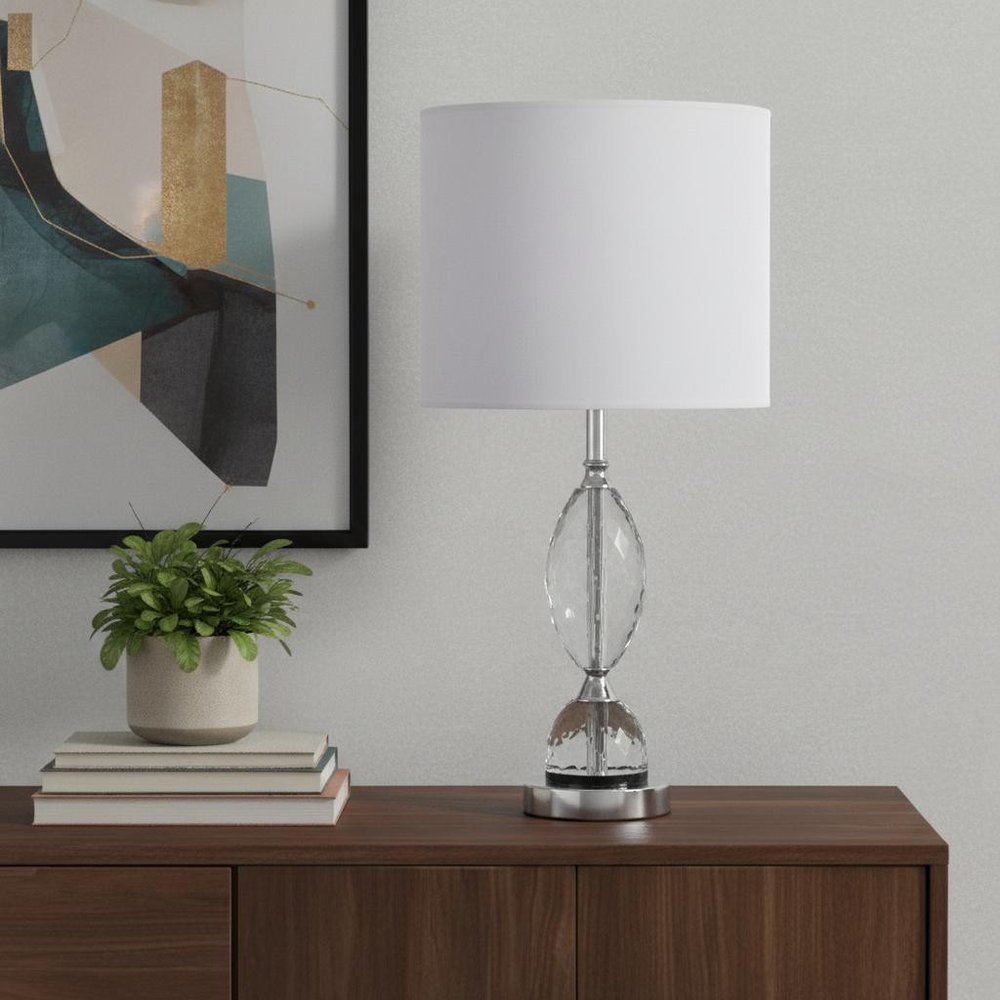 24" Silver Crystal Standard Table Lamp With White Shade displayed on a dark wood tabletop in a furnished interior against a light gray wall.