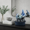 11" Blue Polyresin Dolphins Tabletop Fountain styled in a furnished interior with a light gray wall on a black floor.