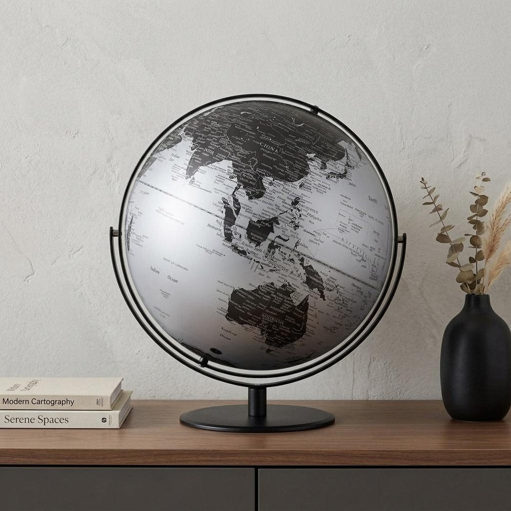 21" Black And Silver Modern Polyresin Globe styled in a furnished interior with a light gray wall on a charcoal floor.