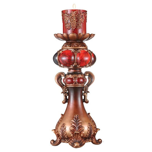A bronze and red ornate polyresin tabletop pillar candle holder with a decorative red candle on a white background.