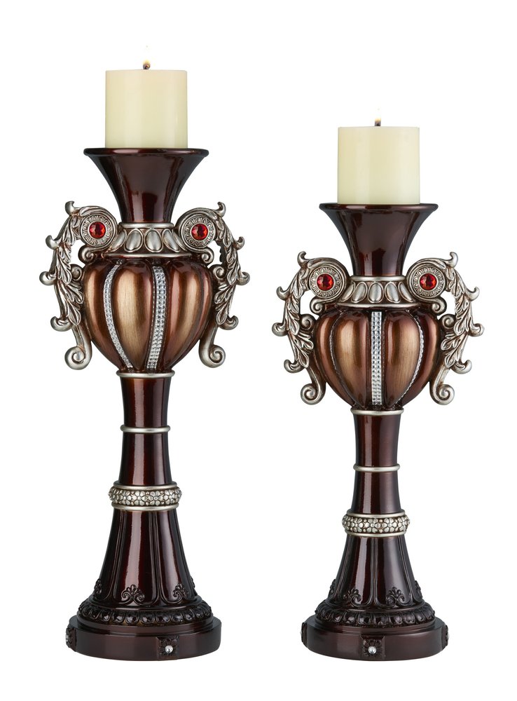 Two ornate bronze urn-shaped pillar candle holders with red jewel accents and cream candles on a white background.