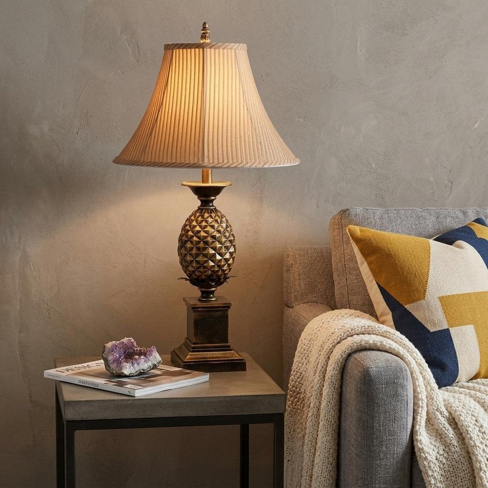 32" Gold Metal Pineapple Table Lamp With Gold Classic Empire Shade displayed on a dark wood tabletop in a furnished interior against a tan wall.