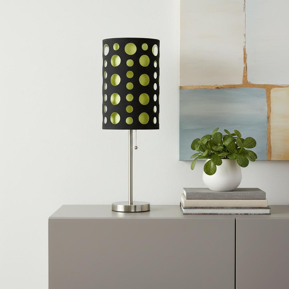 33" Silver Metal Mod Table Lamp With Black And Green Drum Shade displayed on a tabletop in a furnished interior against an off-white wall.