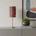 33" Gray and Red Mod Dot Novelty Table Lamp displayed on a tabletop in a furnished interior against a light gray wall.