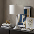 28" Silver Metal Bedside Table Lamp With White Shade displayed on a tabletop in a furnished interior against a tan wall.