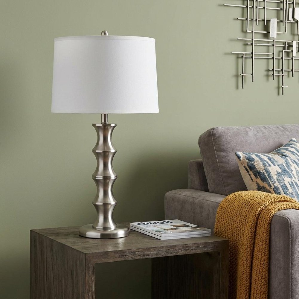 30" Black Solid Wood Bedside Table Lamp With White Shade displayed on a tabletop in a furnished interior against a gold wall.