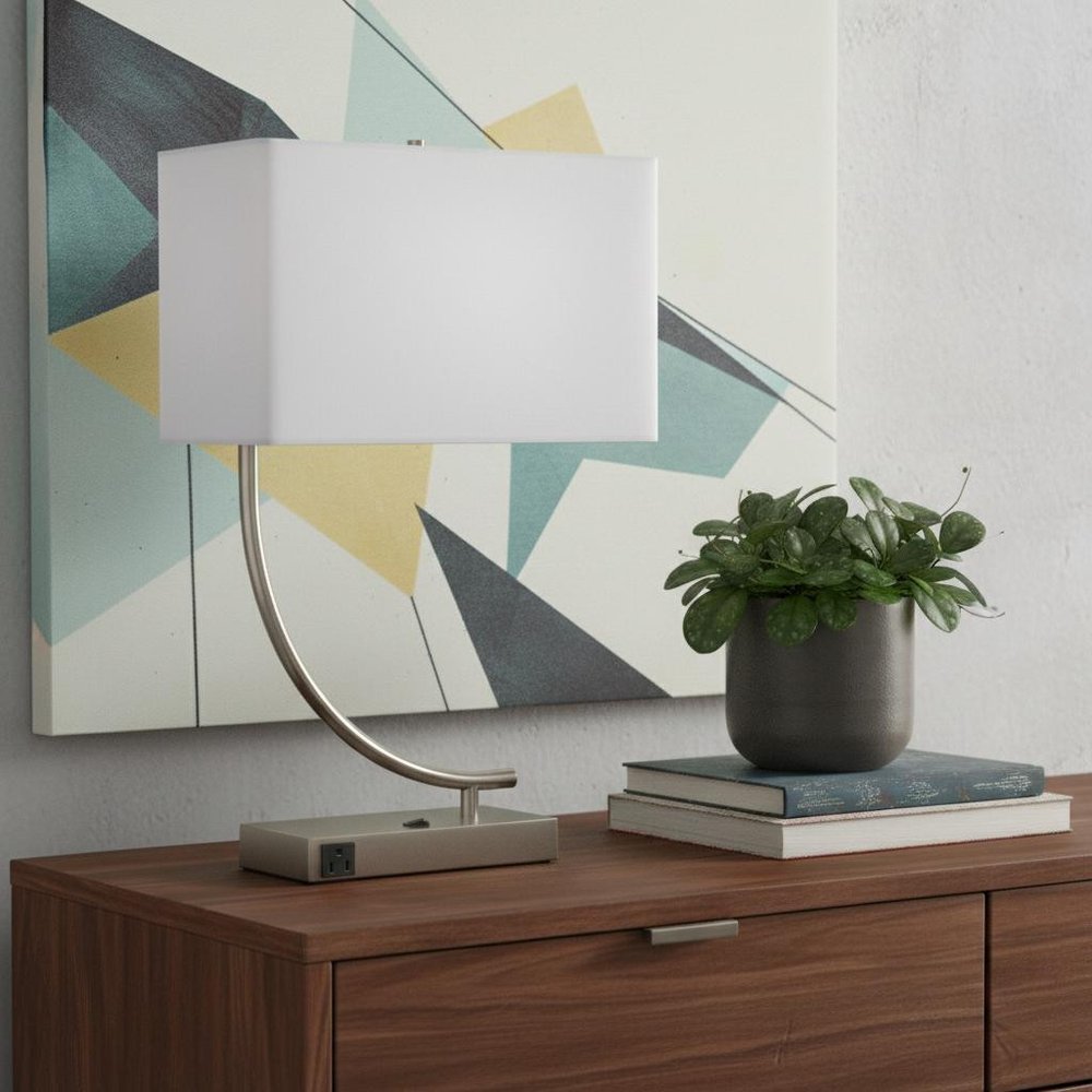 23" Silver Curved Table Lamp With White Rectangle Shade displayed on a dark wood tabletop in a furnished interior against an off-white wall.