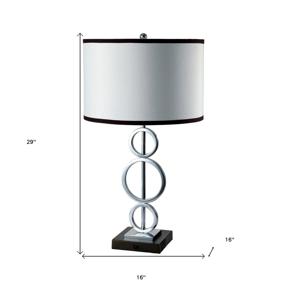 29" Silver Metal Bedside Geo Table Lamp With White and Black Trim Classic Drum Shade. Table lamp isolated on a plain white background, finished in silver metal.
