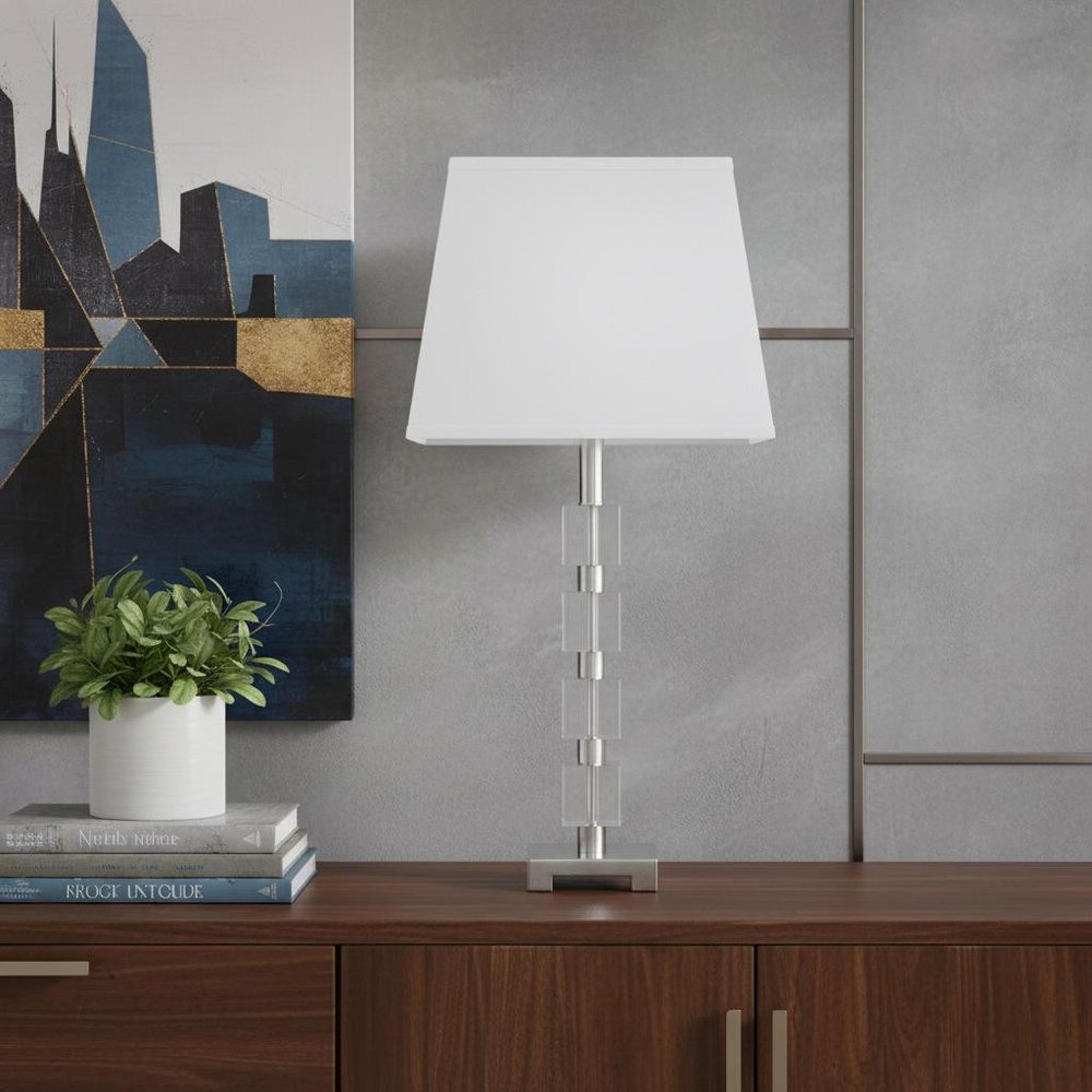 25" Crystal Geo Cubed Table Lamp With White Sharp Corner Square Tapered Shade displayed on a dark wood tabletop in a furnished interior against a gray wall.