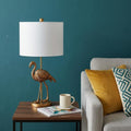 26" Gold Flamingo Table Lamp With White Drum Shade shown outdoors on an outdoor setting.