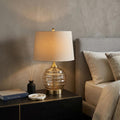 23" Off-White Metal Bedside Table Lamp With Off-White Shade displayed on a tabletop in a furnished interior against a tan wall.