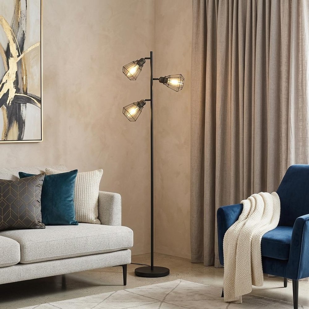 66" Black Metal Three Light Tree Floor Lamp With Black Metal Cage Shade standing in a furnished interior on a wood floor.