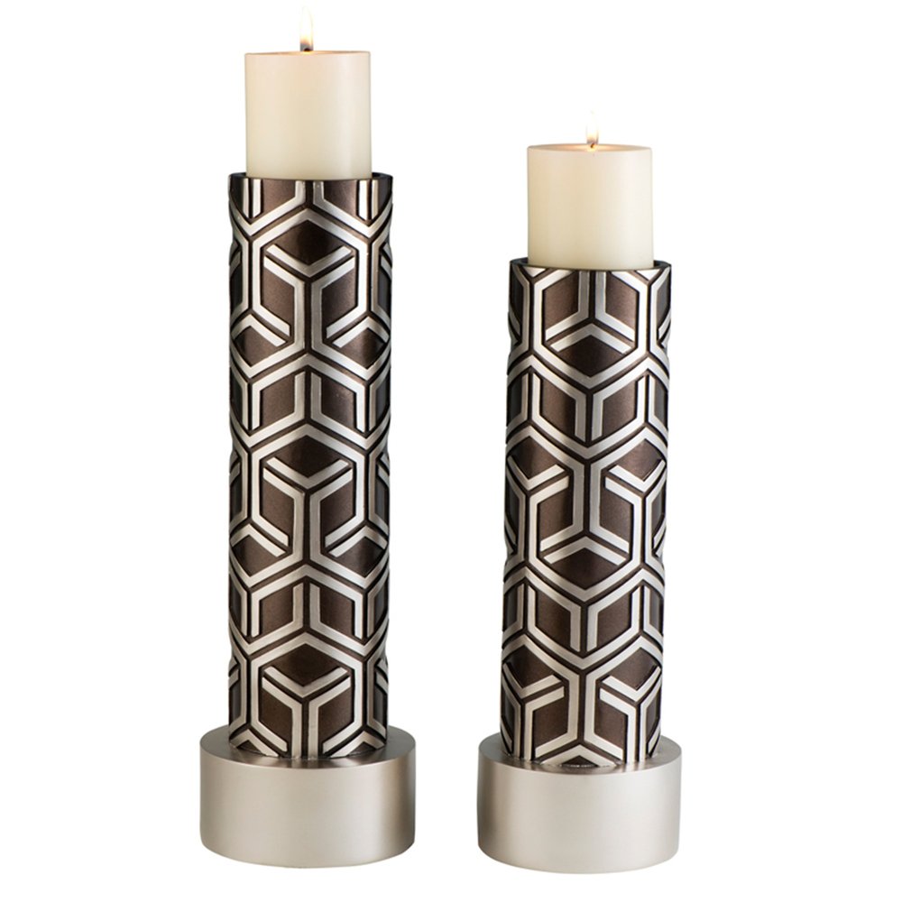 Two espresso and silver geometric pillar candle holders with white pillar candles on a white background.