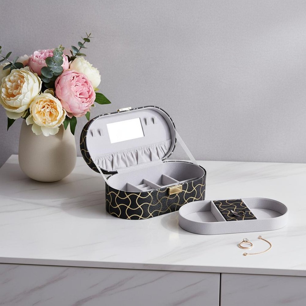 10" Black And Gold Faux Leather Abstract Scroll Jewelry Box Travel Case With Mirror styled in a furnished interior with a light gray wall on a tiled floor.