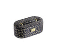 Black and gold faux leather oval jewelry box with abstract scroll pattern and gold hardware, isolated on a white background.