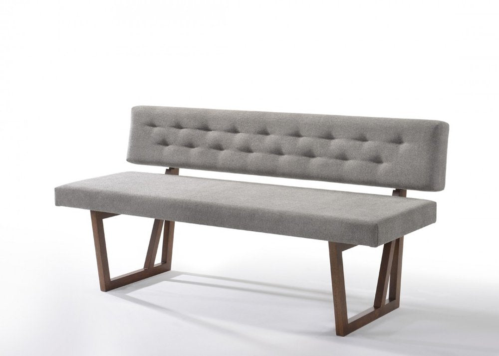 Gray upholstered dining bench with tufted back and brown wooden legs on a white background.