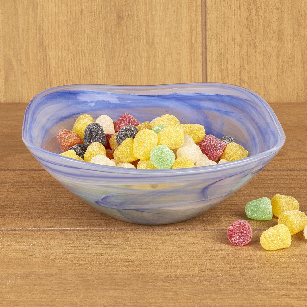 Blue and white swirled glass candy bowl filled with colorful gumdrops on a wooden surface.