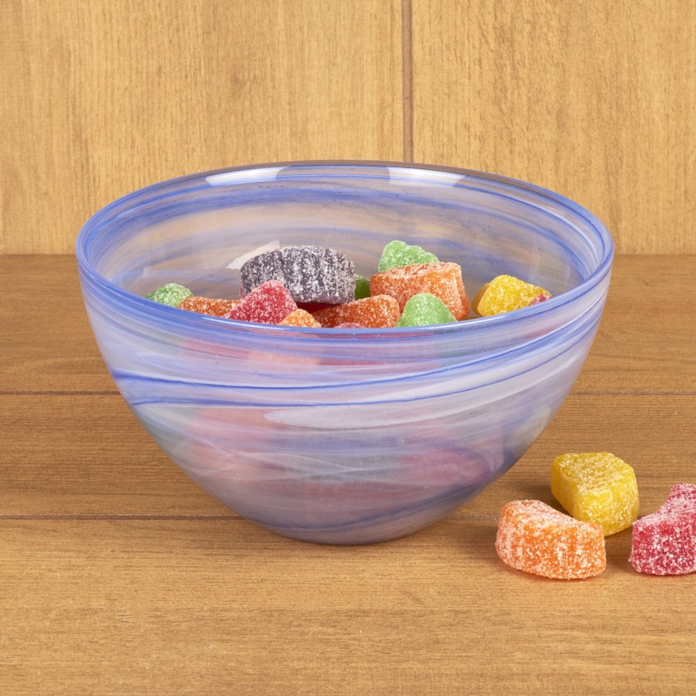 A blue and white swirled glass bowl filled with colorful gummy candies sits on a wooden surface.