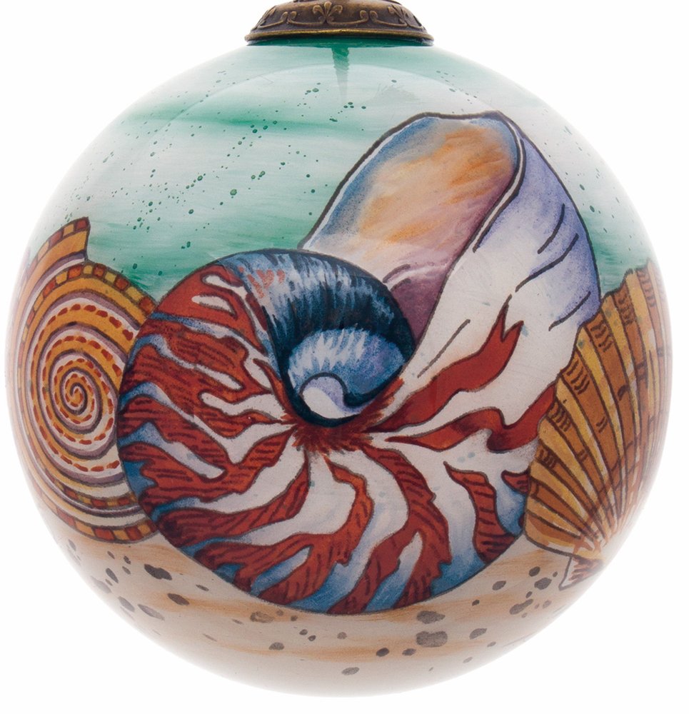 Hand-painted mouth-blown glass ornament featuring nautilus and seashell designs on a sandy beach with a green, speckled background.