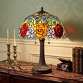 24" Dark Brown Metal Two Light Candlestick Table Lamp With Orange Shade displayed on a tabletop in a furnished interior against a gold wall.