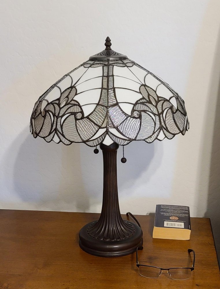 24" Dark Brown Metal Two Light Candlestick Table Lamp With Dark Brown Shade displayed on a dark wood tabletop in a furnished interior against an off-white wall.