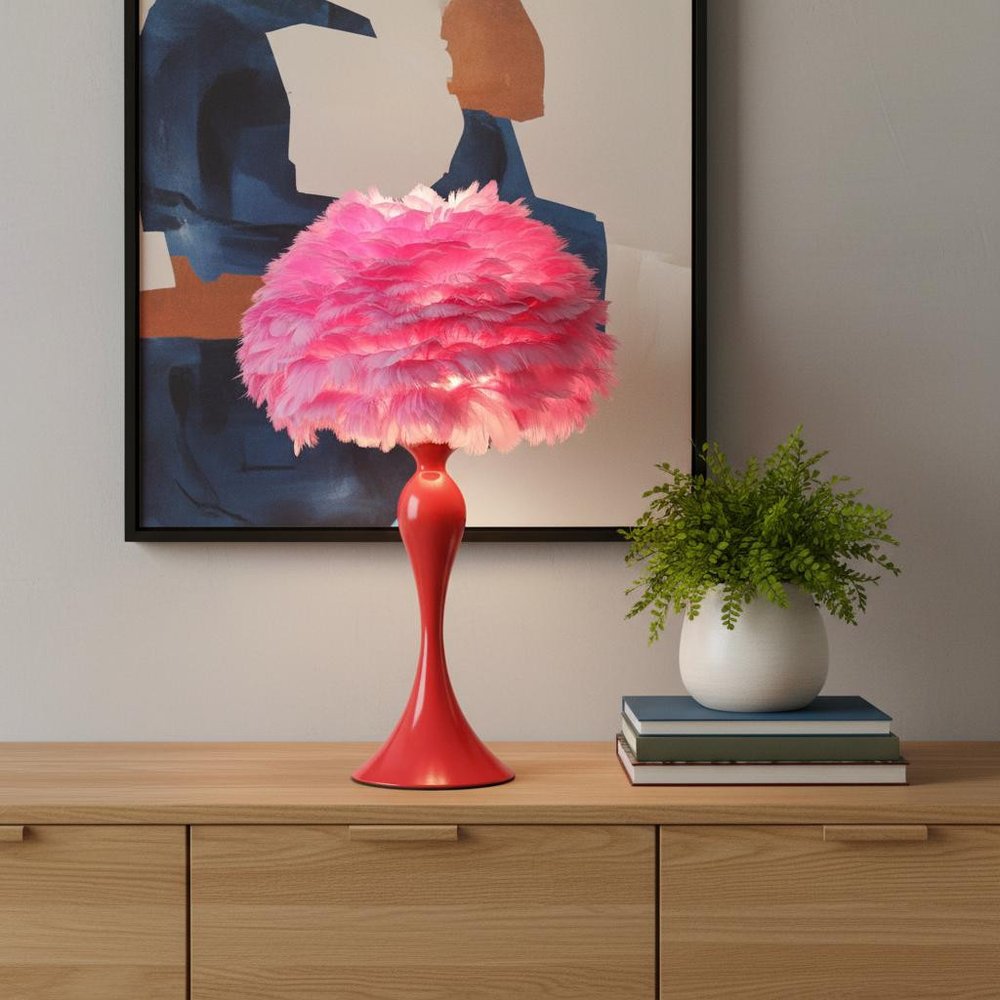 24" Glam Hot Pink Feather and Red Table Lamp displayed on a wood tabletop in a furnished interior against a tan wall.