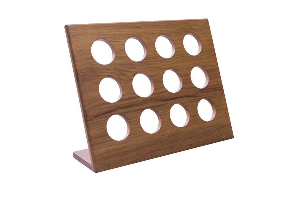 Wooden coffee pod holder with 12 circular openings, angled on a white background.