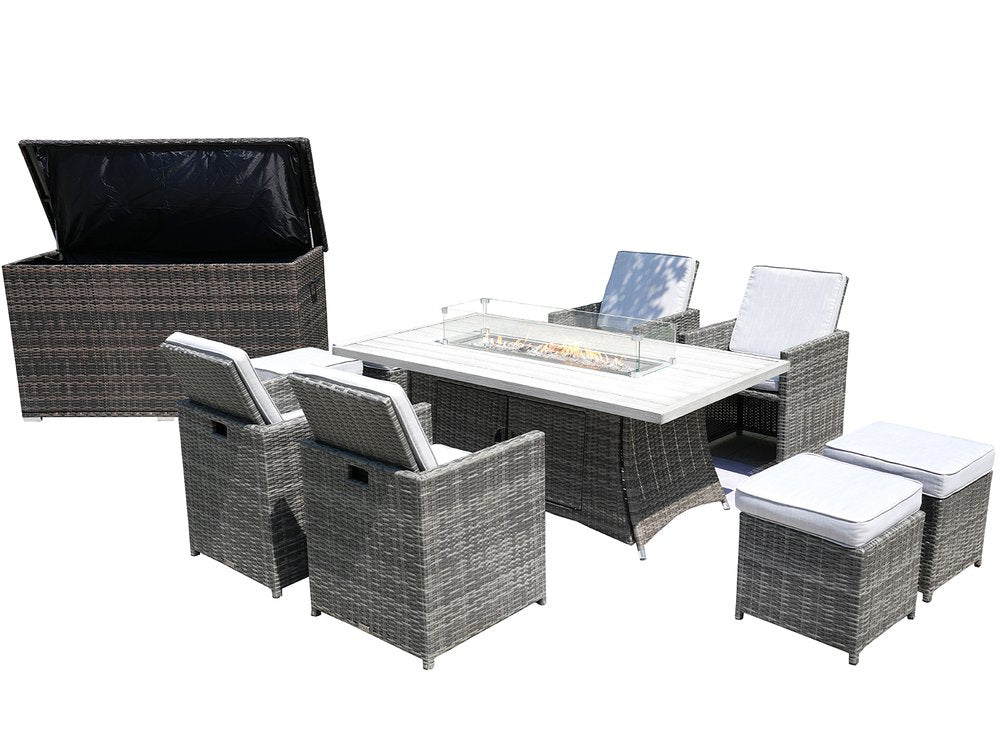 Gray wicker outdoor seating group with white cushions, including a fire pit table, four chairs, and two ottomans, with a storage box.