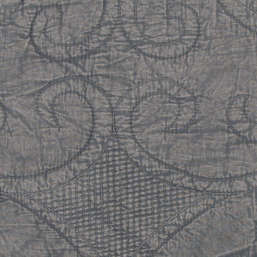 Close-up of a gray damask quilt with swirling stitched patterns and a diamond-shaped quilted section.