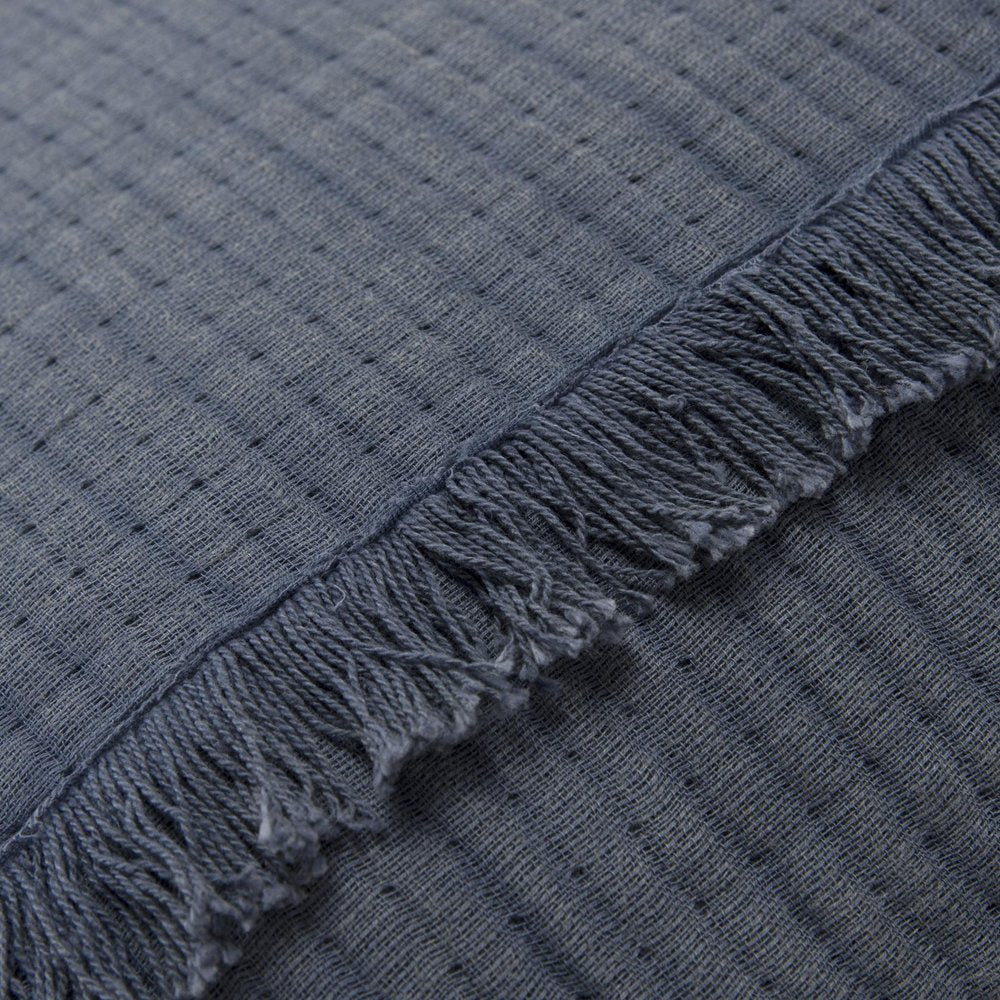 Close-up of a blue checkered queen quilt with fringe detail.