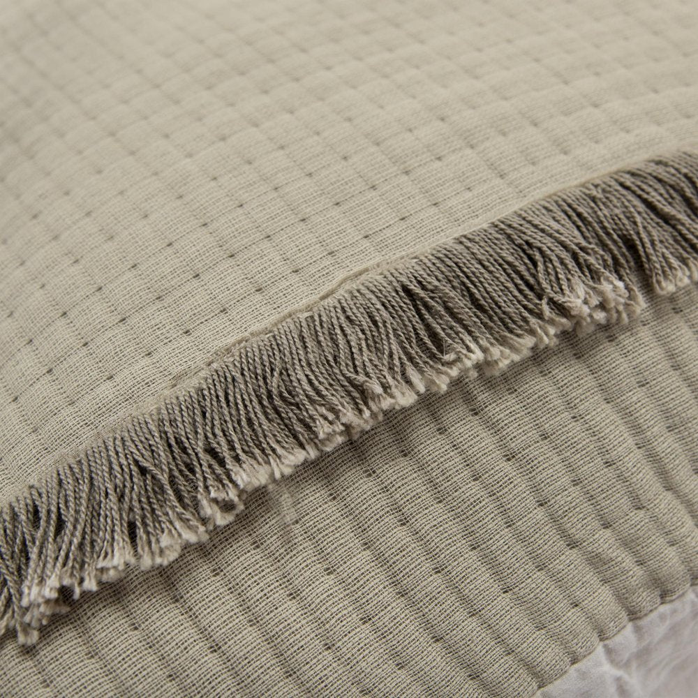 Close-up of a natural checkered queen quilt with fringed edges, showing textured fabric and stitching.