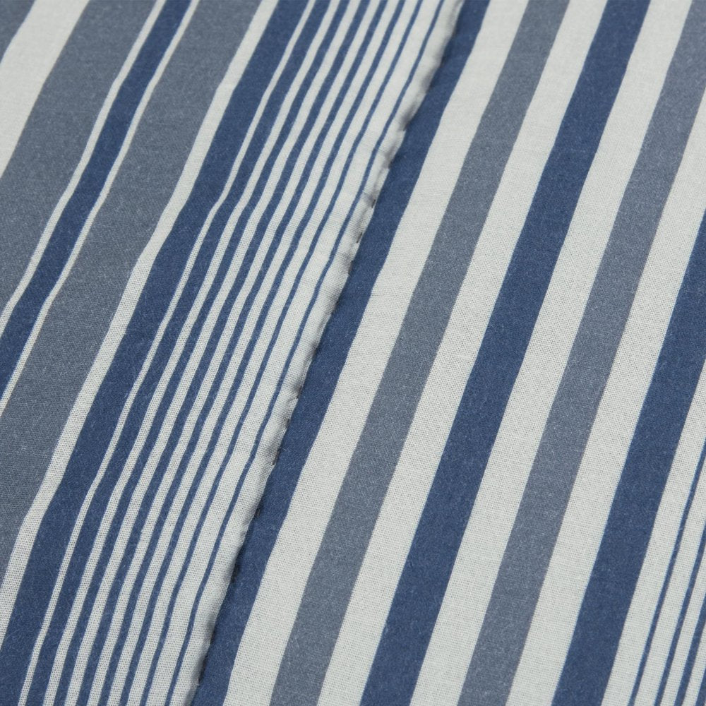 Close-up of a blue and white striped king quilt with a textured finish.