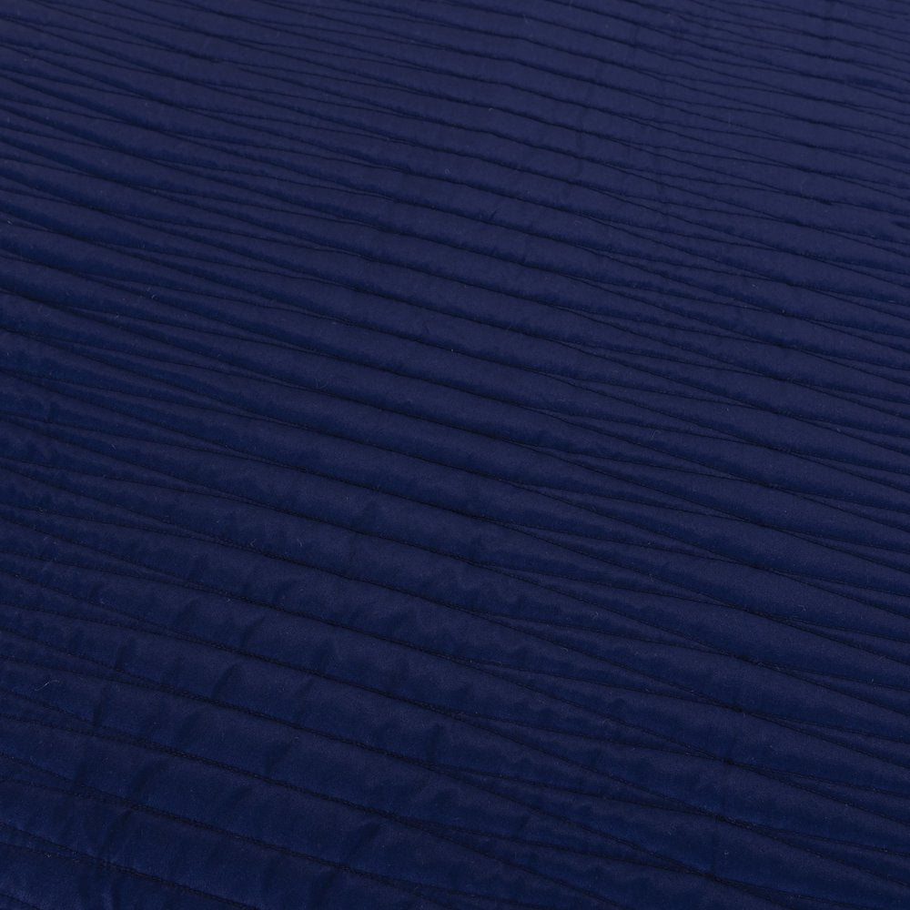 Close-up of an indigo geometric queen quilt with textured stitching.