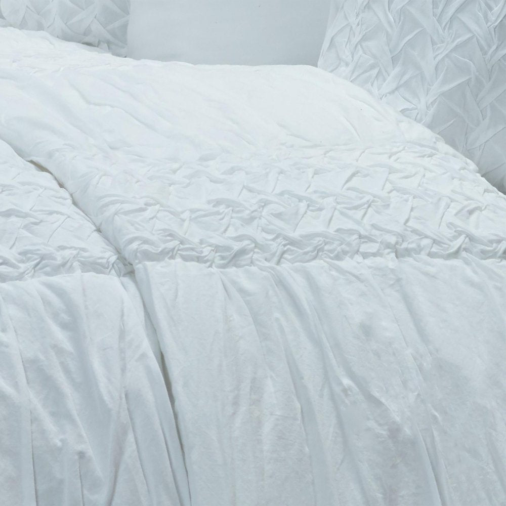 Close-up of a white geometric queen quilt with textured fabric and a soft, rumpled appearance.