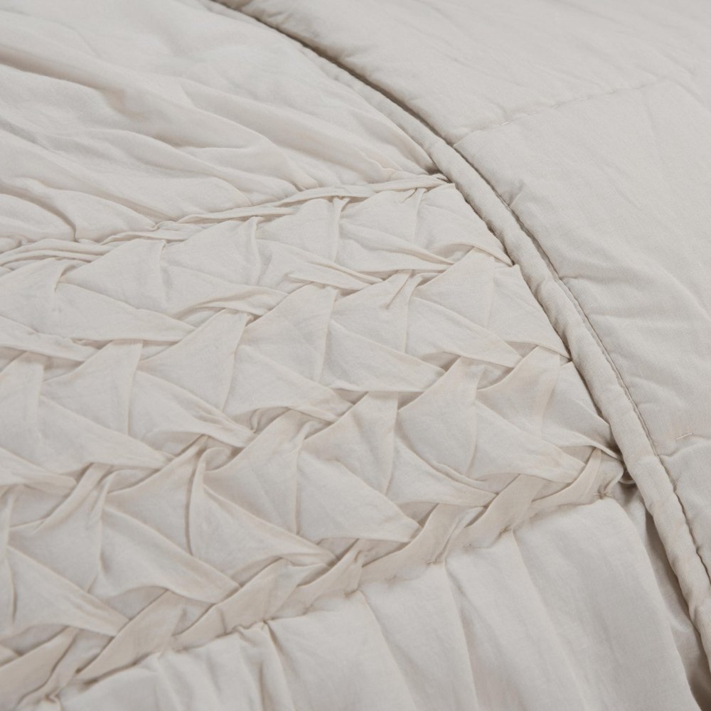 Close-up of an ivory geometric quilt with textured fabric and stitched detailing.