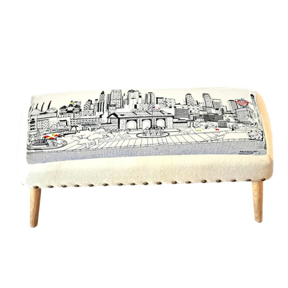 Cream wool ottoman with a black and white city skyline print and wooden legs.