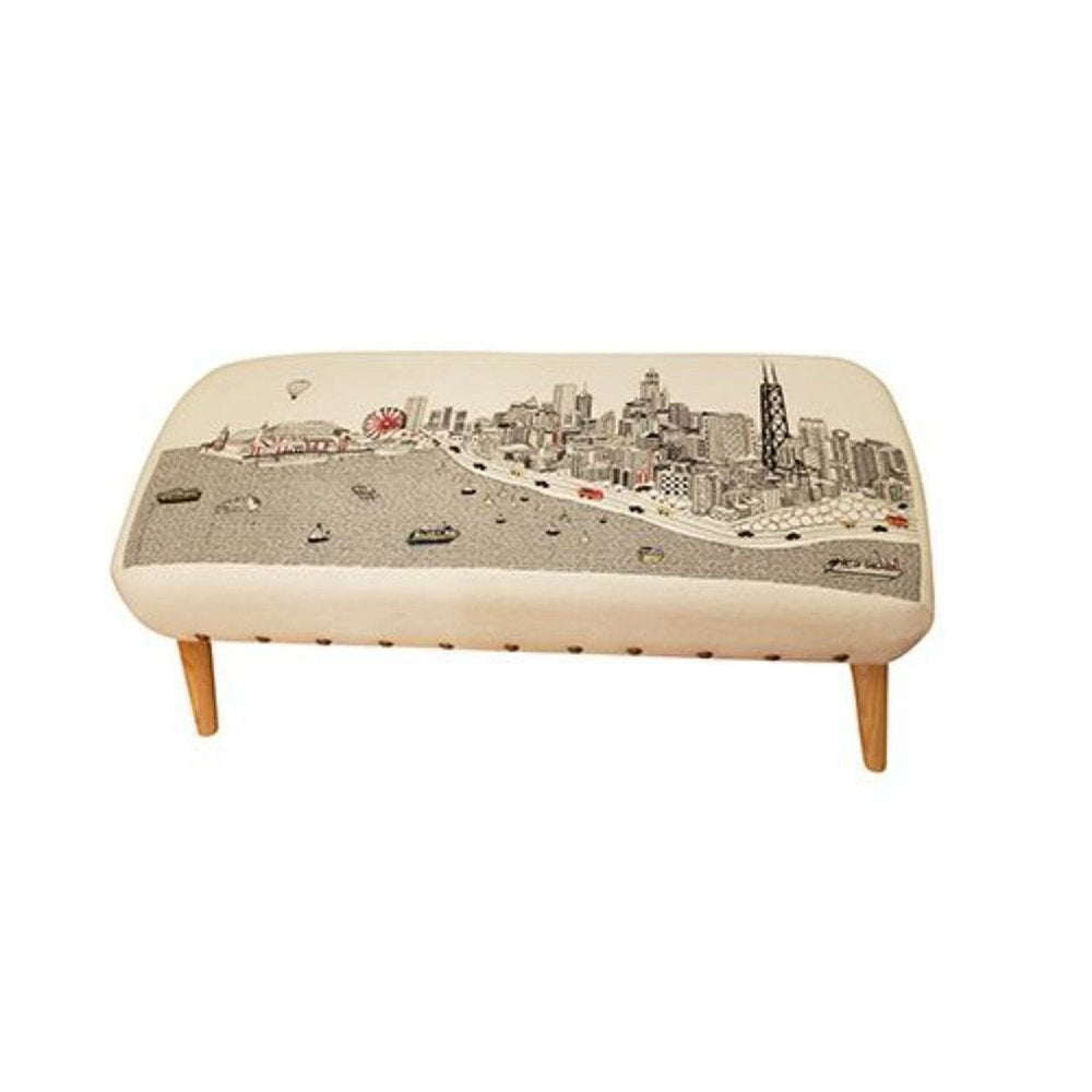Cream wool ottoman with a black and white city skyline print and wooden legs.