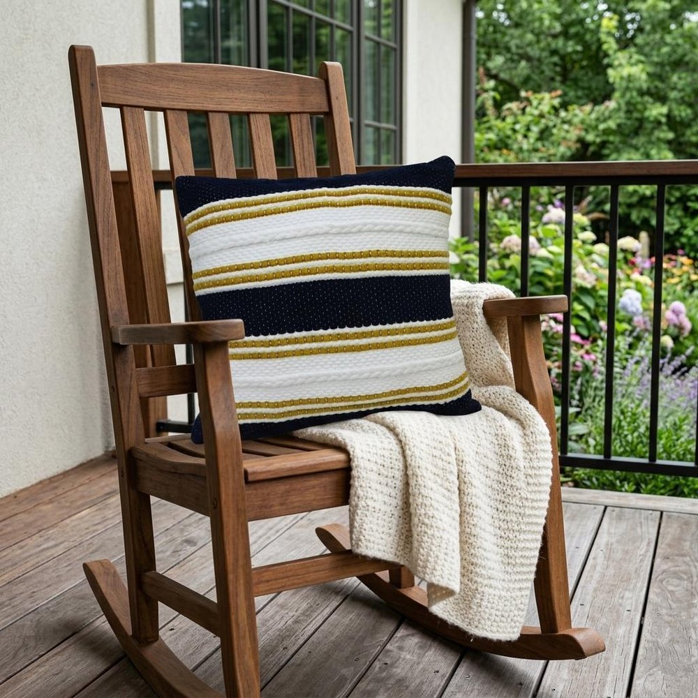 18" X 18" Black And Yellow Zippered Striped Indoor Outdoor Throw Pillow shown outdoors on a patio with greenery.