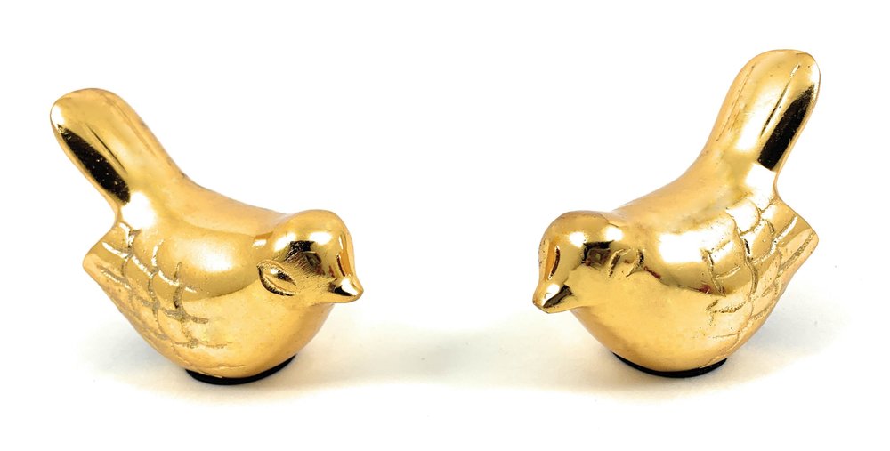 Two gold metal bird sculptures facing each other on a white background.