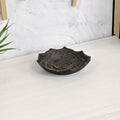 Black metal tray with a rose design on a white wooden surface with a textured gray wall in the background.