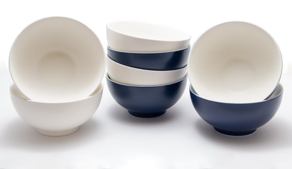 Four white and navy blue porcelain bowls stacked and arranged on a white background.