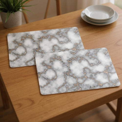 Two rectangular gray and gold abstract agglomerated cork placemats on a wooden table.