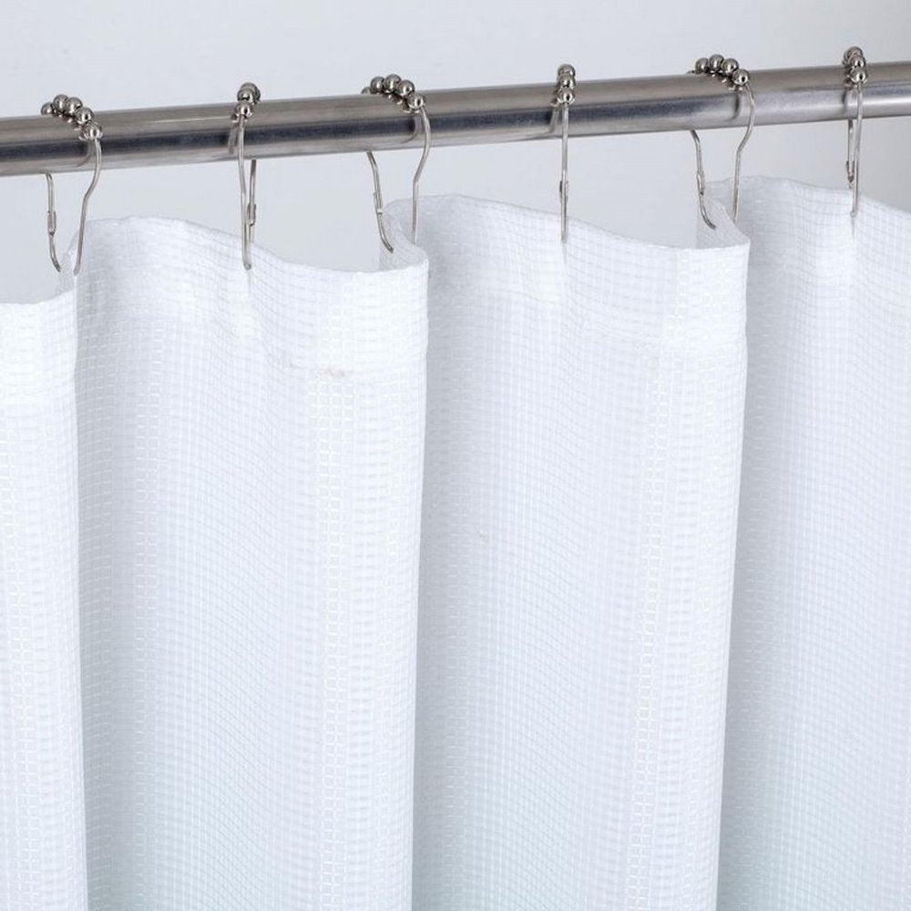 White waffle weave shower curtain with silver roller hooks hanging from a metal rod against a white background.