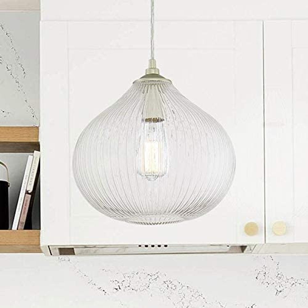 Clear glass ribbed pendant light with silver hardware hangs above a white kitchen island and range hood.