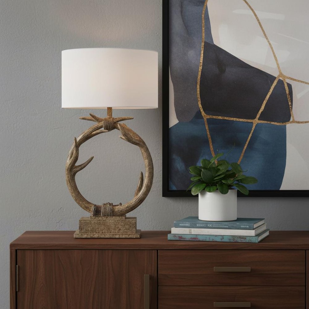 27" Brown Rustic Faux Antlers Table Lamp With White Drum Shade displayed on a dark wood tabletop in a furnished interior against a gray wall.