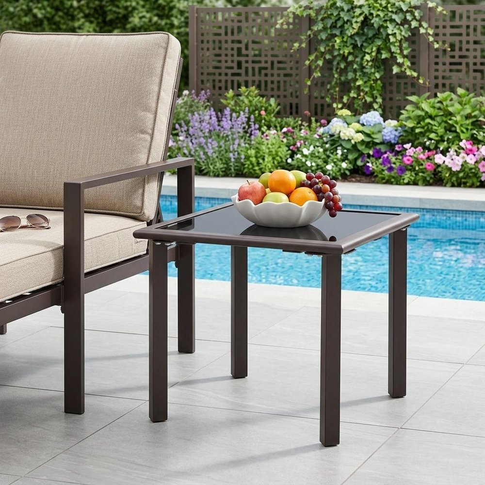 18" Black Square Glass Outdoor Side Table shown outdoors on a tiled patio with greenery.