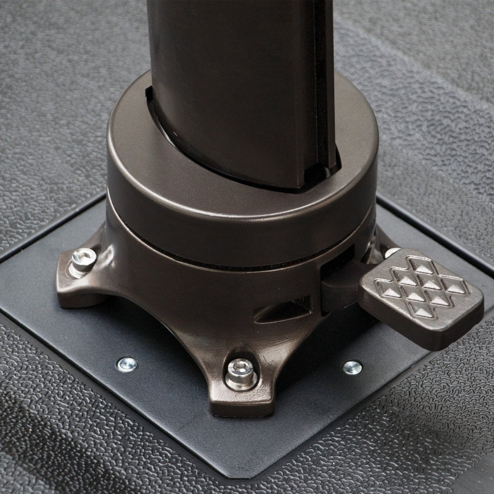 Close-up of a dark bronze umbrella base with a foot pedal on a textured black surface.